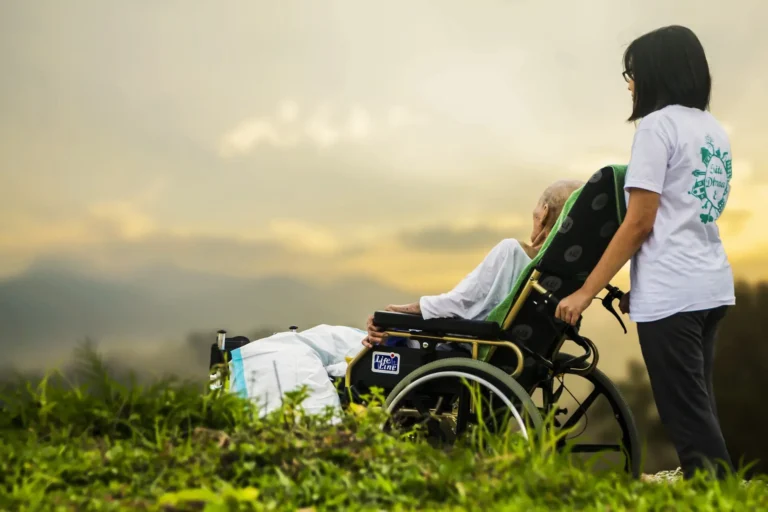 a woman pushing an old man in a wheelchair