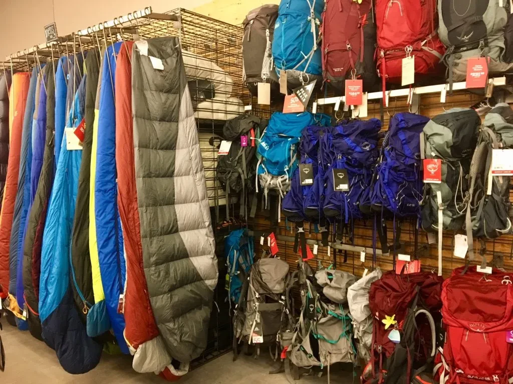 a rack of sleeping bags and backpacks